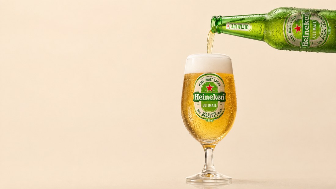 Copo Heineken com colarinho de espuma ao lado da garrafa Ultimate, líquido dourado translúcido.